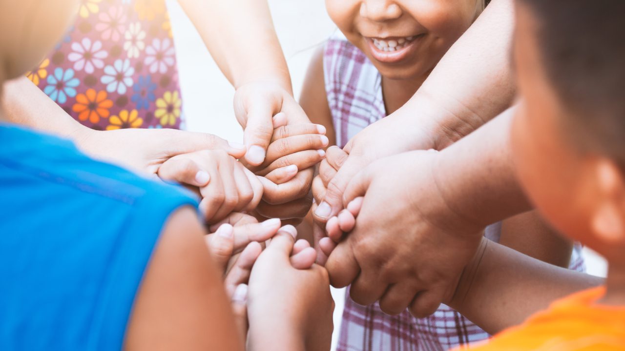 A group of people holding hands in the middle of a circle.